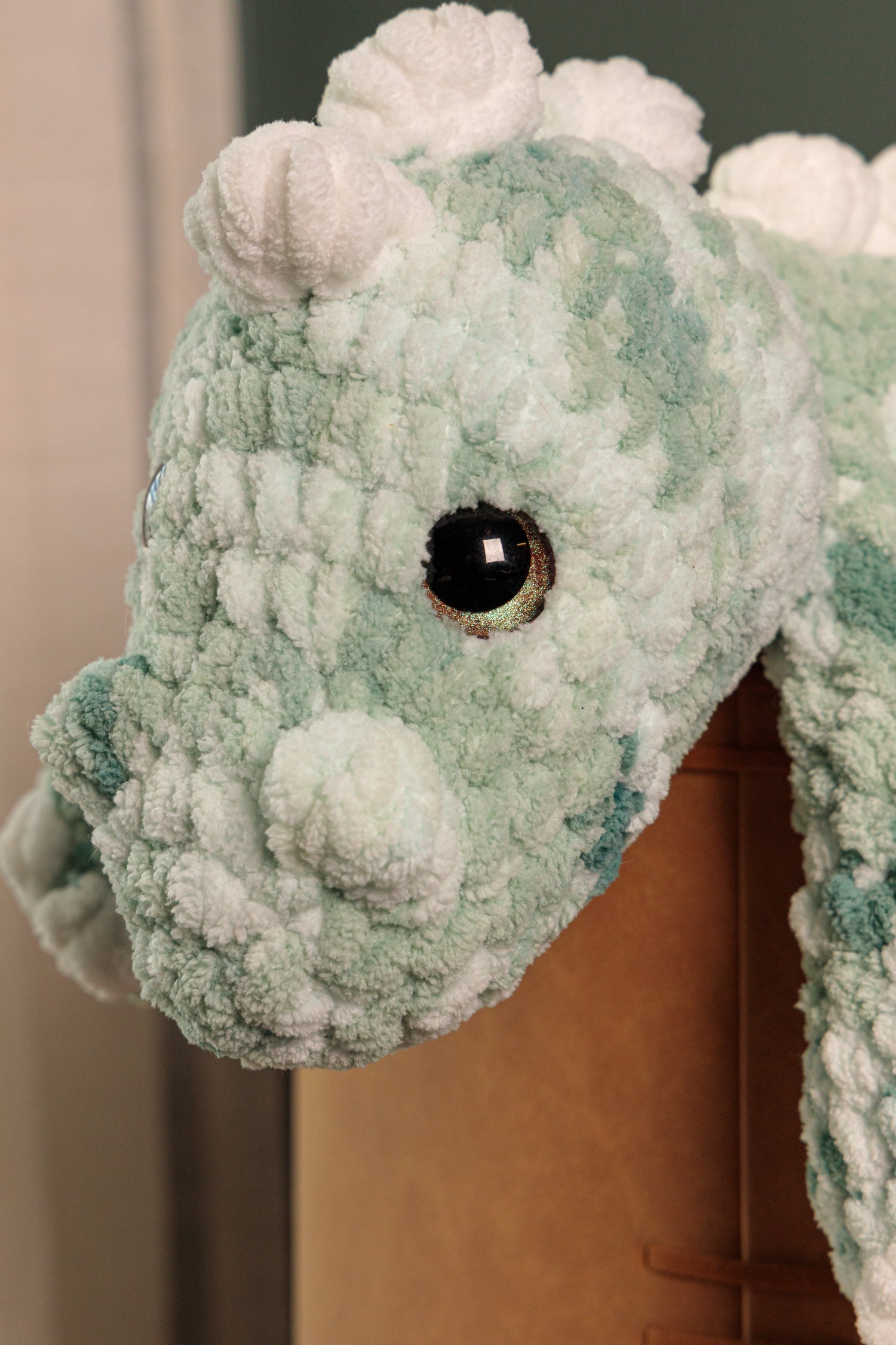Handmade pale green plush toy with large safety eyes, crocheted in blanket yarn.