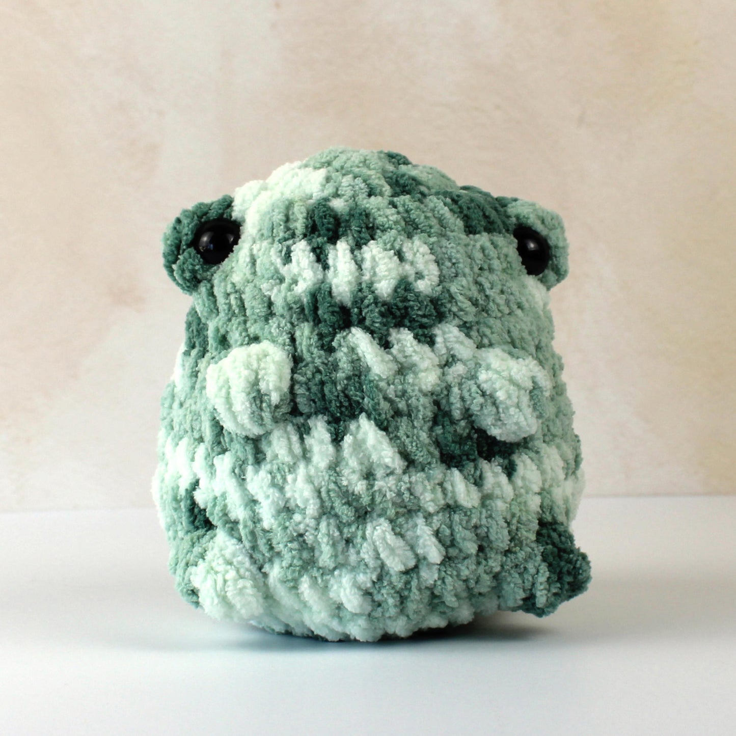Handmade crochet frog plush toy in green variegated blanket yarn, soft gift for kids or collectors.