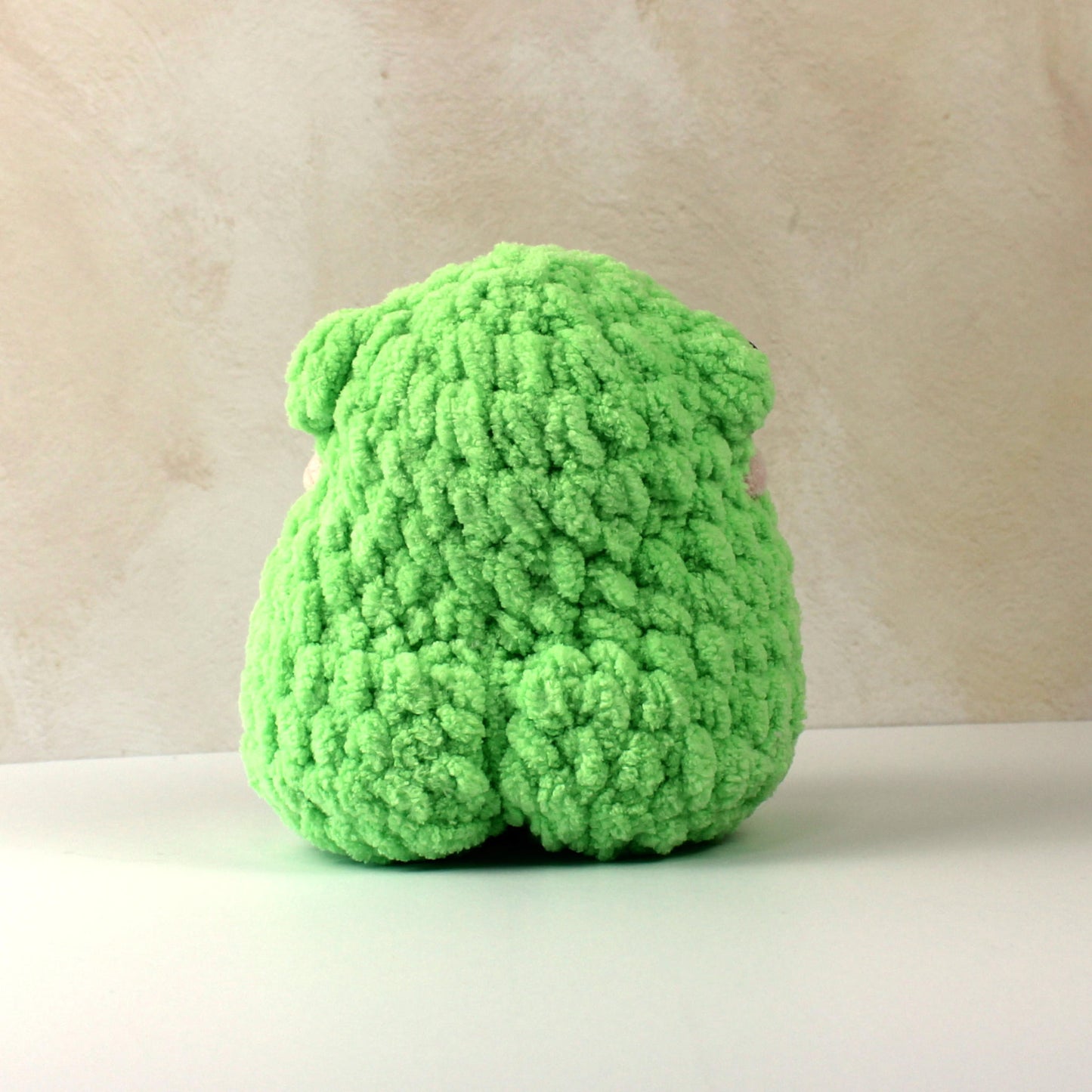 Handmade crochet frog plush toy in bright green blanket yarn, soft gift for kids or collectors.