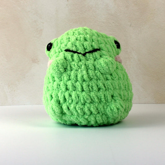 Handmade crochet frog plush toy in bright green blanket yarn, soft gift for kids or collectors.