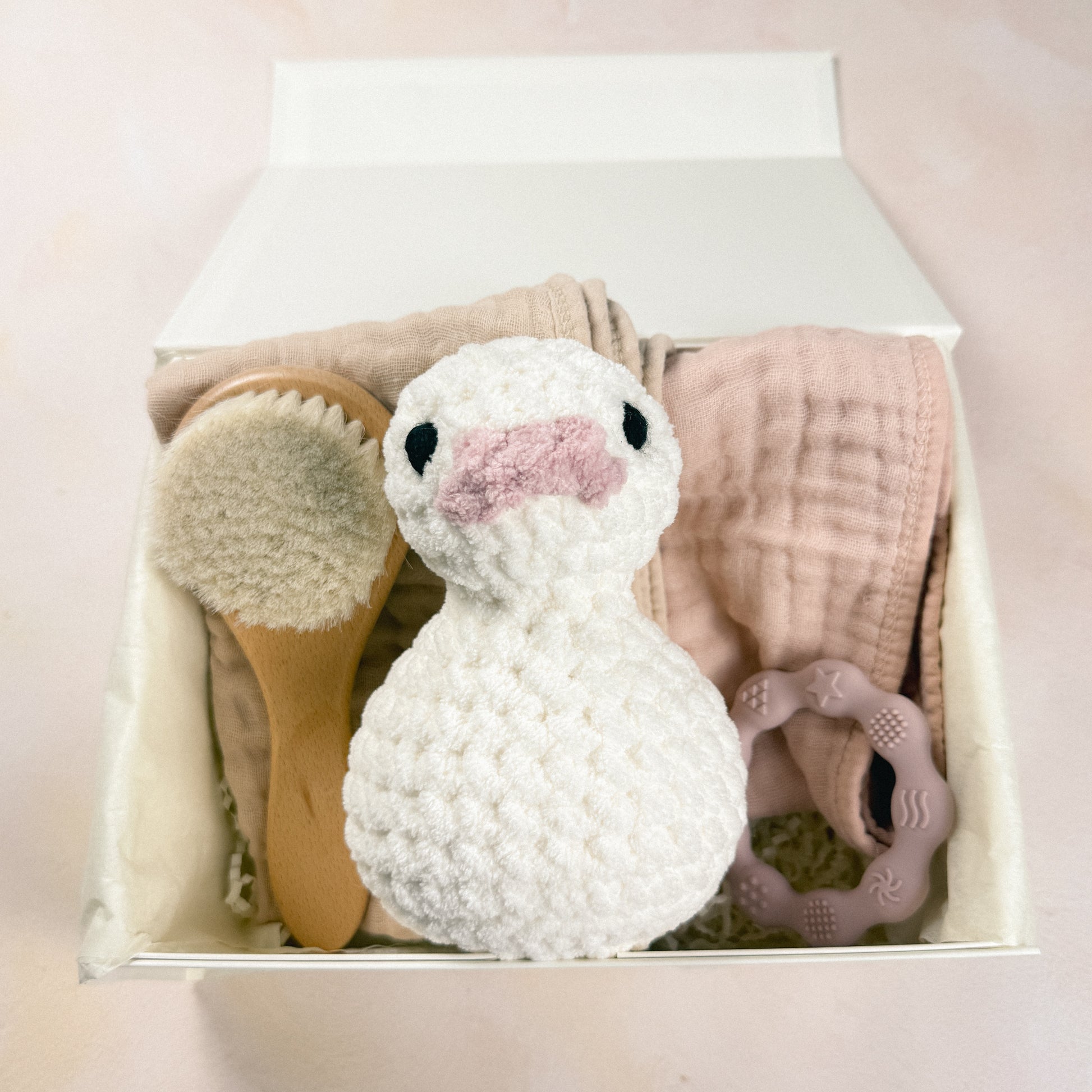 Petal & Pearl First Days Edit arranged inside a magnetic gift box with plush duck, burp cloths, baby brush, and teether.