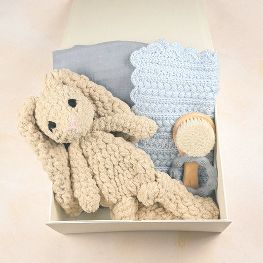 Keepsake Edit arranged inside a magnetic gift box with plush bunny, crochet security blanket, swaddle, baby brush, and teether.