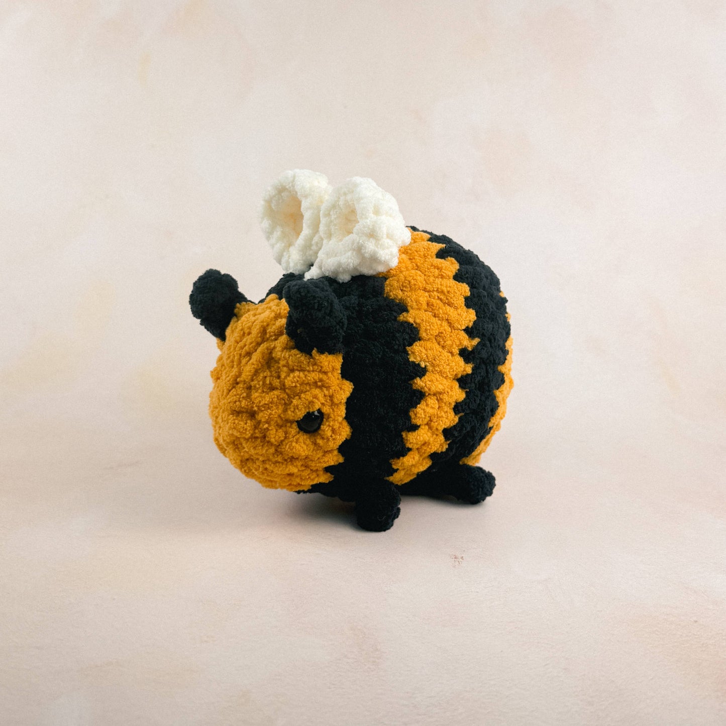 Crocheted bee plush shown on a light neutral background.