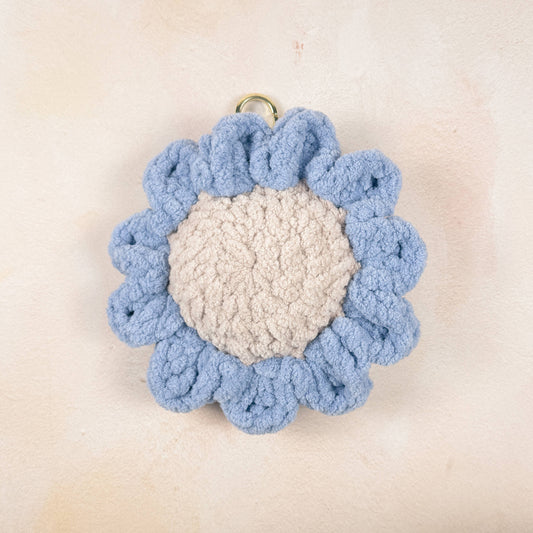 Crochet blue daisy chain charm laid flat on a neutral background  flower detail.