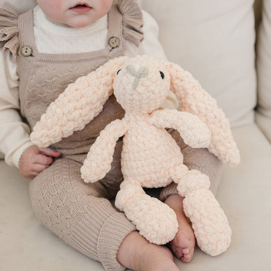 Child holding a plush bunny toy on a light-colored couch to show scale.