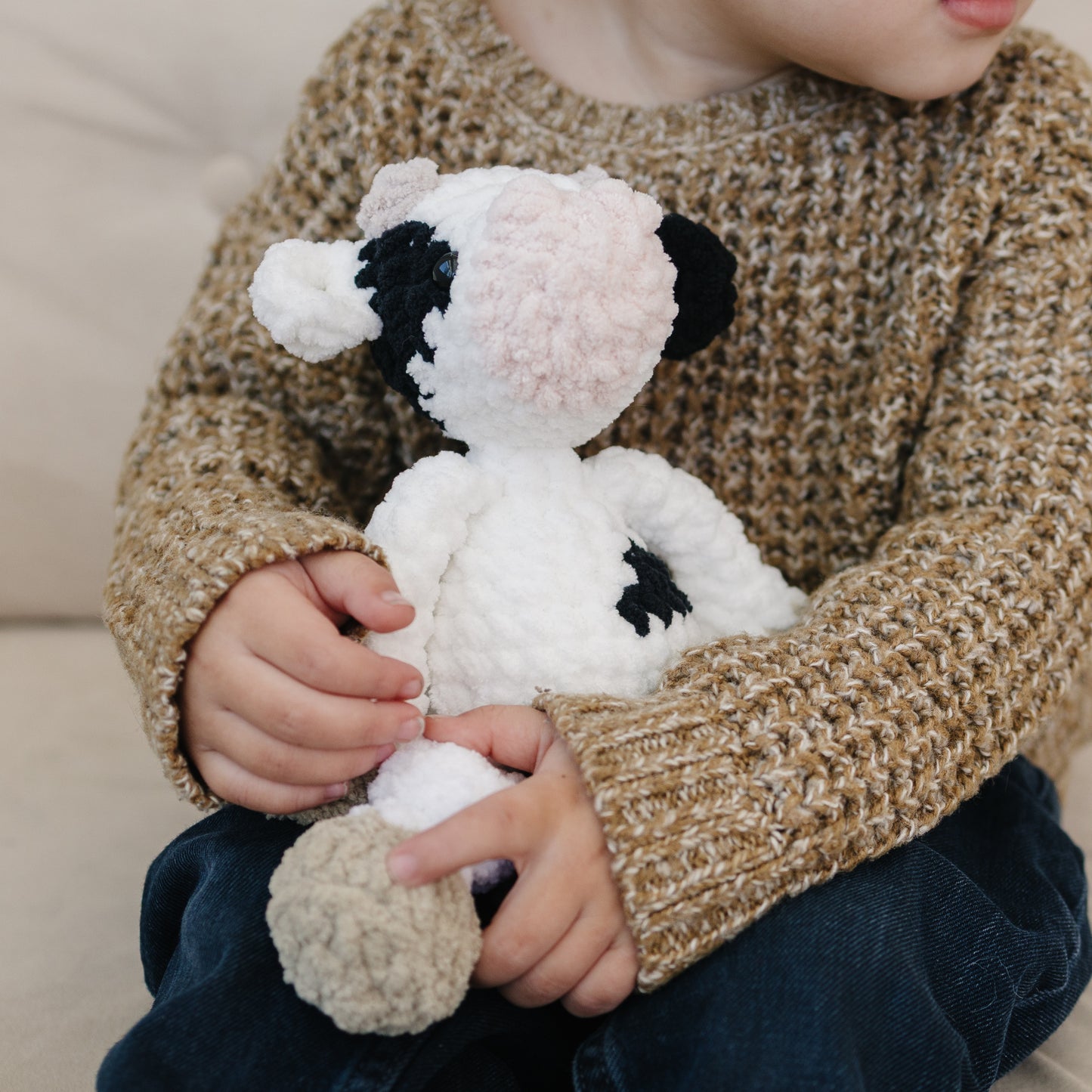 Black and white cow plush held in a child’s hands to show size and texture.