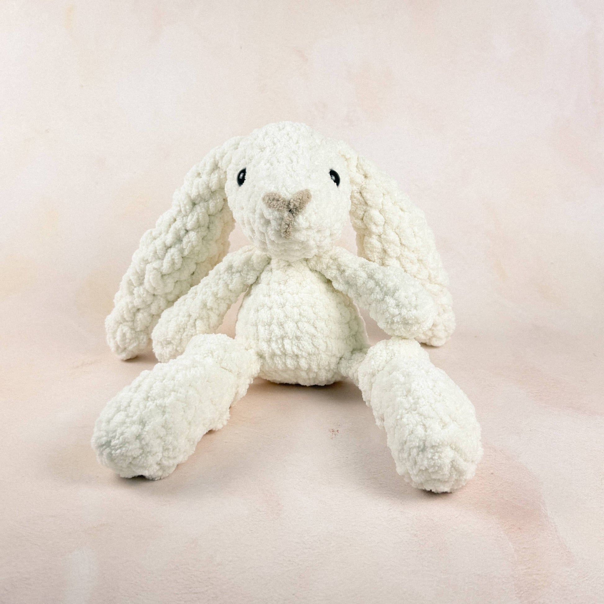 Crocheted cream bunny plush shown on a light neutral background.