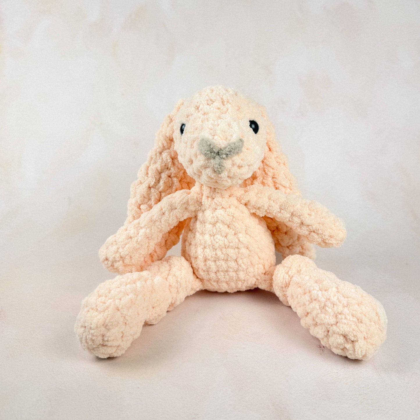 Peach bunny plush shown on a light neutral background.